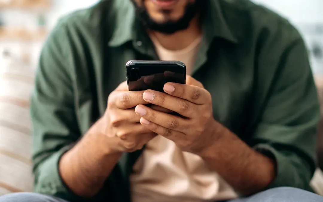 An adult man holding a mobile phone with both hands