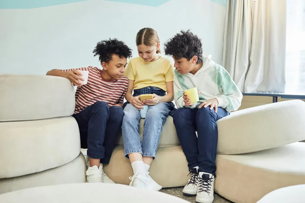 Three pre-teen kids looking at a mobile phone