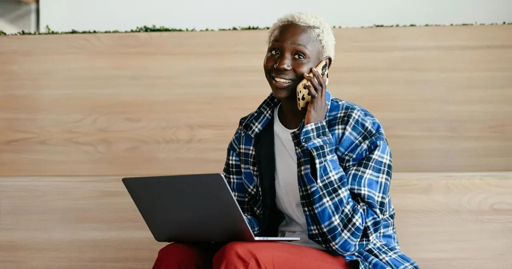 A happy woman on the phone with a laptop